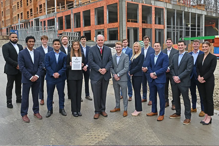 A group of people pose in front of a building under construction.