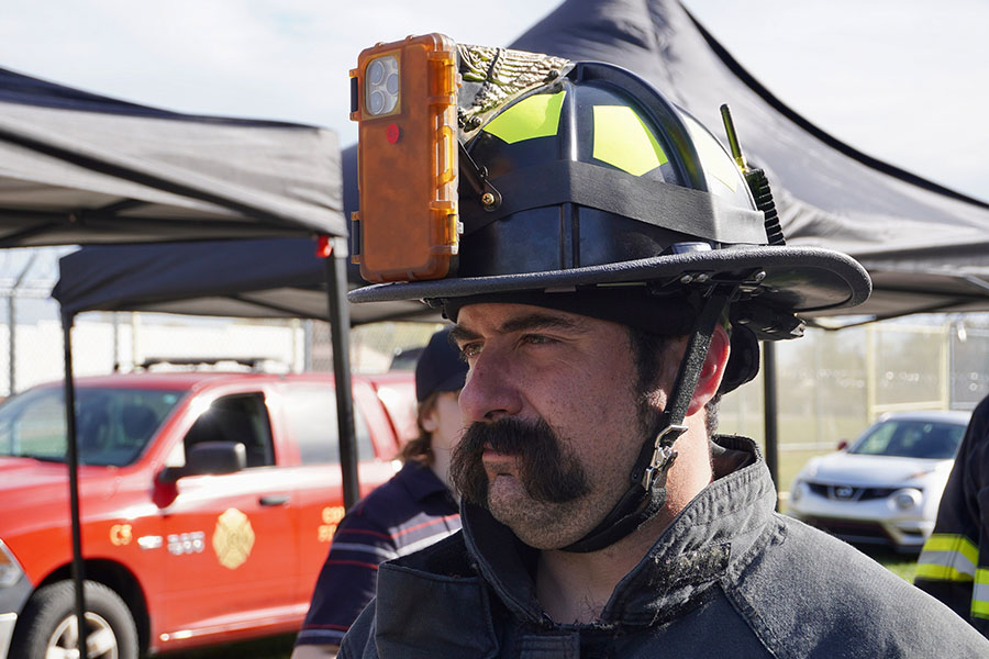 A firefighter shows a camera mounted to the top of his helmet.