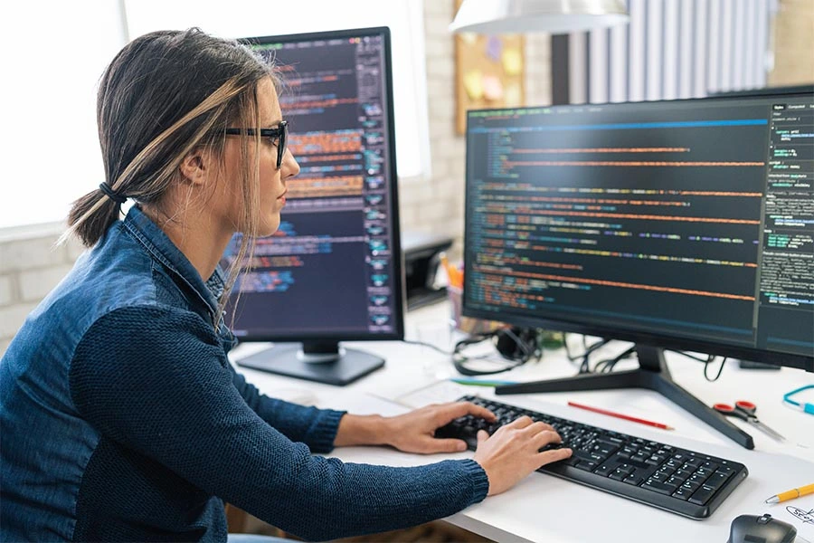 A female student works on programming code on her computer.