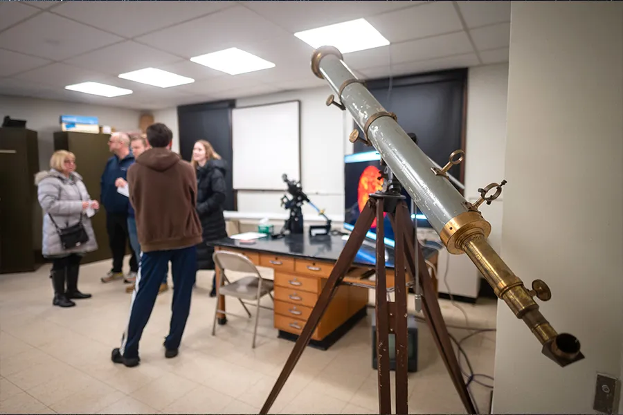 People stand in a room with a telescope