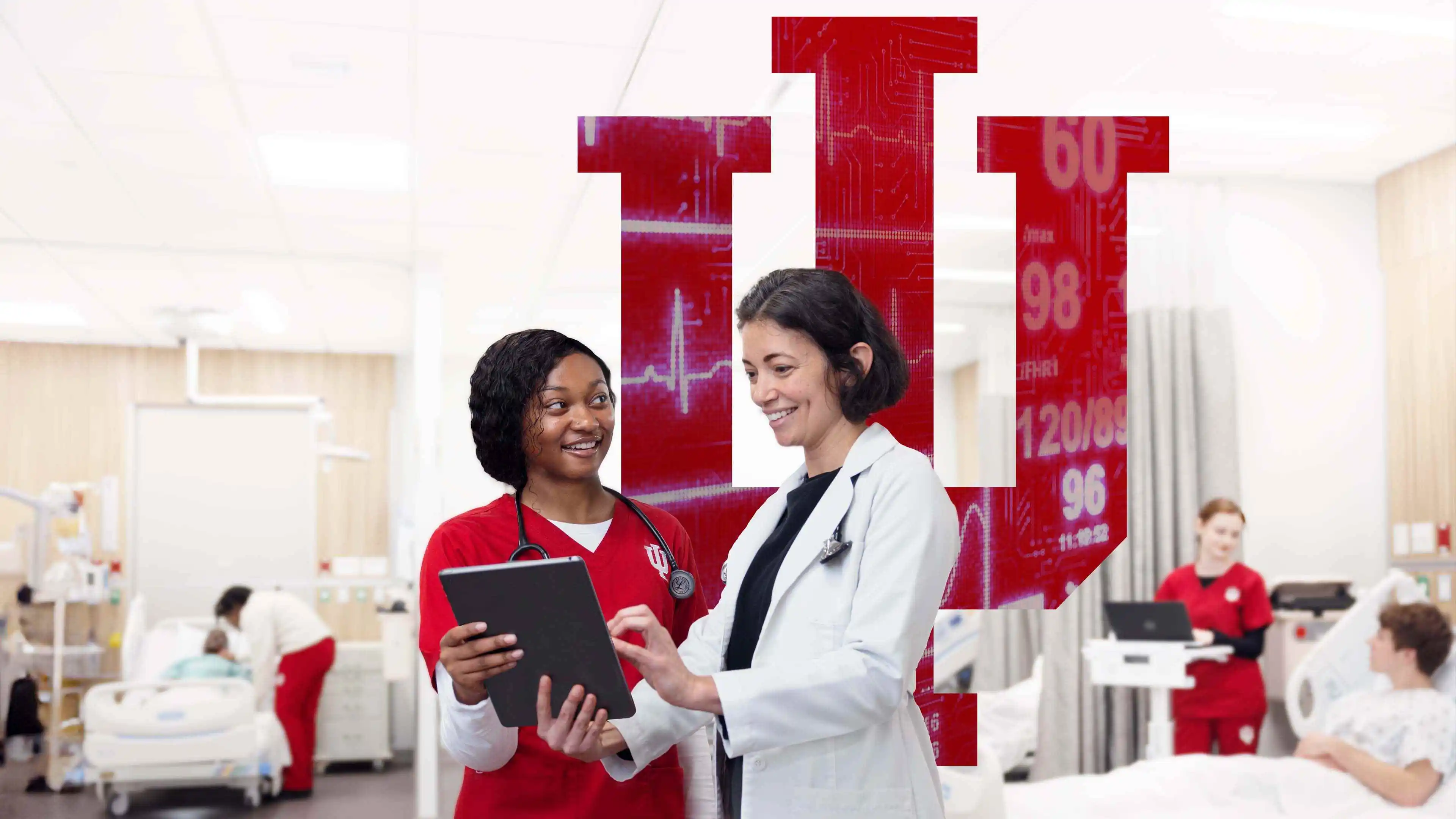 A doctor and nurse review a medical record, while a patient receives medical care from a nurse in the background. The IU trident is overlaid with vital signs.