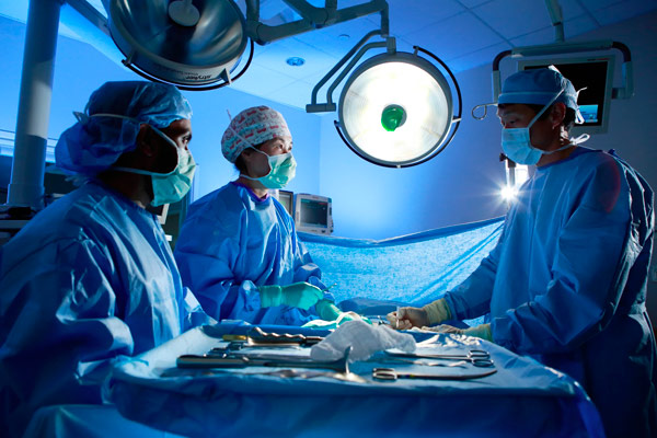 Three IU School of Medicine students stand in blue scrubs around a patient, prepared for surgery