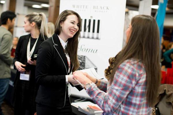 Female undergraduate student talking to an employer at a career fair.