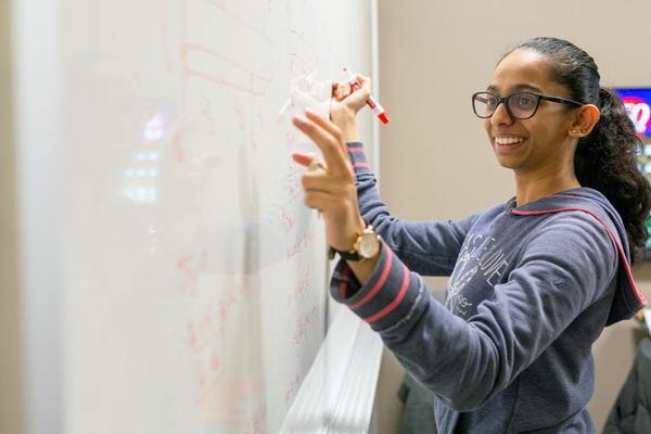 Student writing equations on a whiteboard.