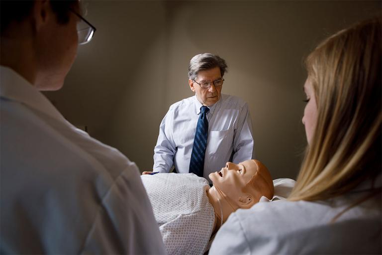 Doctor and students in front of a simulation dummy.