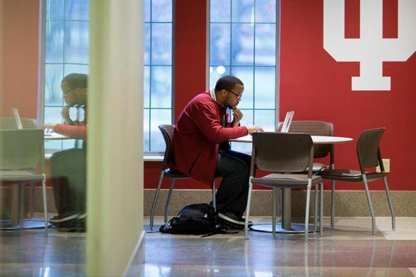 Student studying by himself in front of a large IU trident.