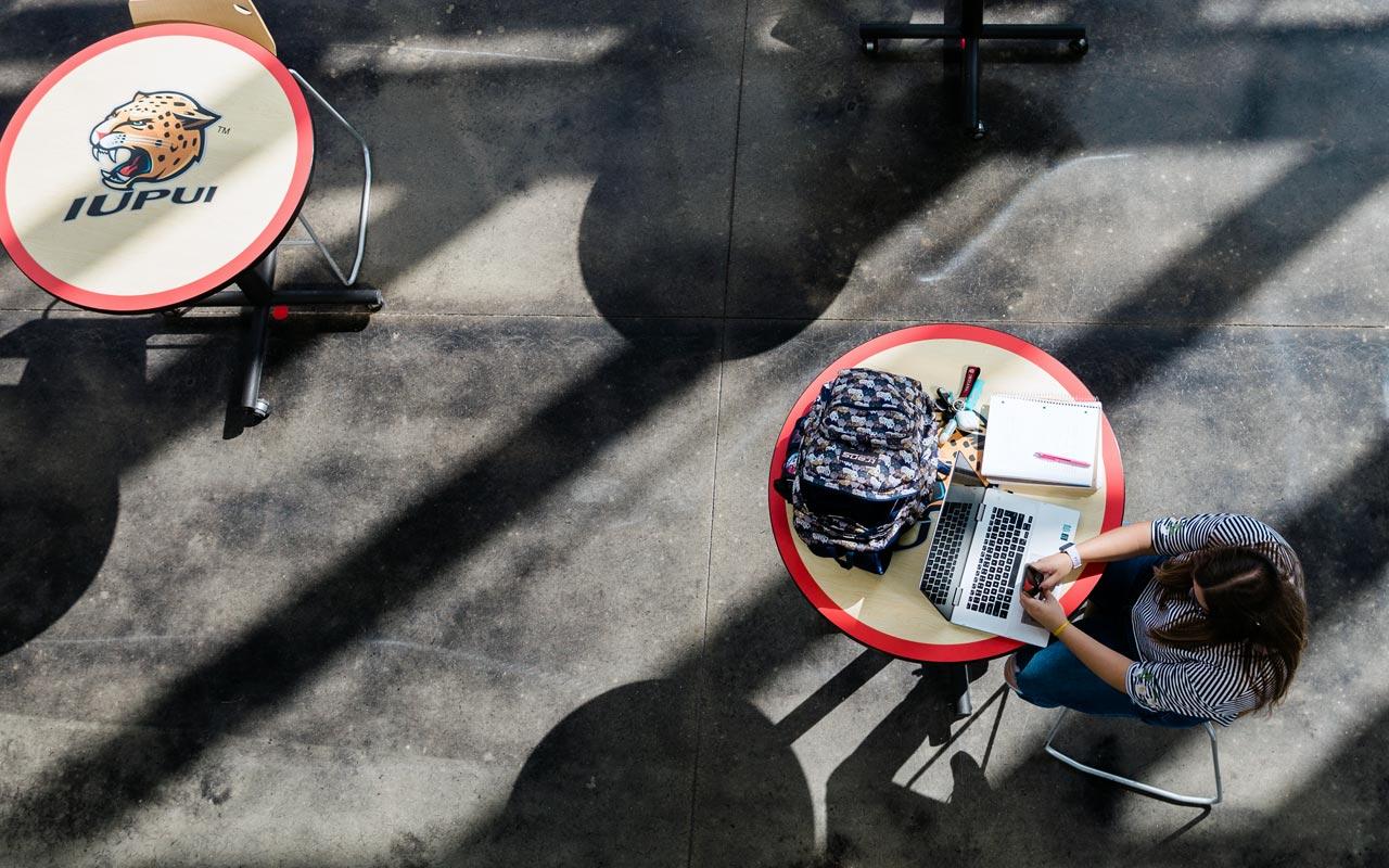 Female IUPUI student sitting by herself at a table.