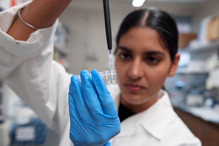 Student drops research sample into tube.