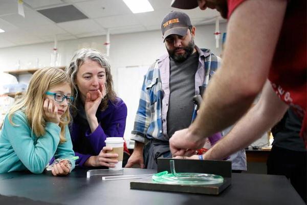 IU Bloomington student helping a child with a science experiment.