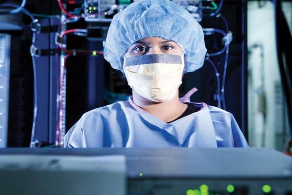 Woman in scrubs standing in front of a computer.