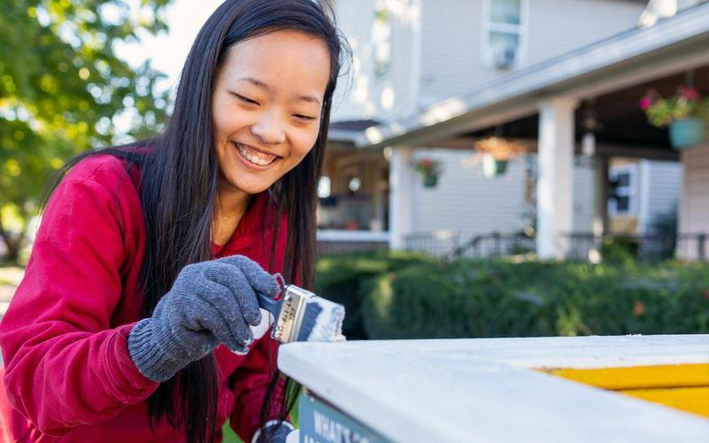 IU student painting a fence.