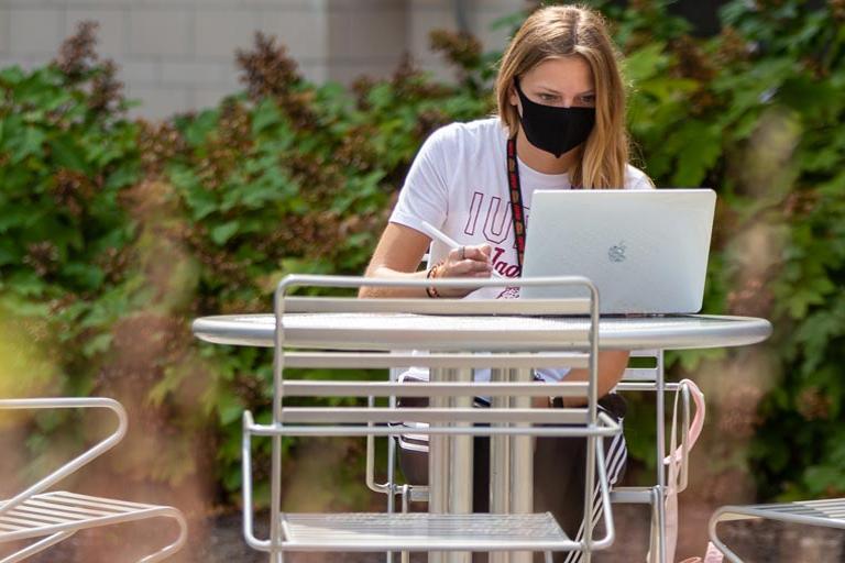 Female IUPUI student studying outside.