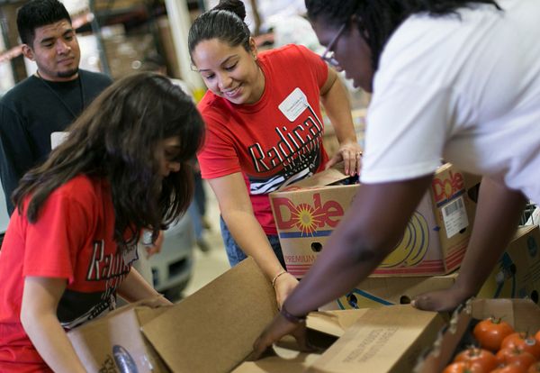 Volunteers handle boxes of food at the Day of Service event at a food bank.
