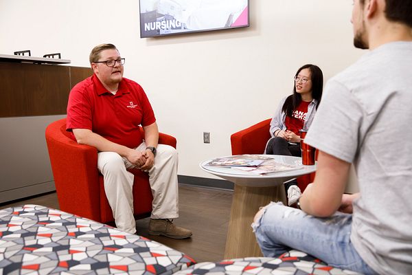 People sit and talk around an office table in the School of Nursing office at IU Fort Wayne.
