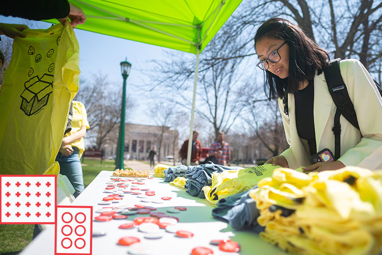 A student looks at a table with pins and t-shirts