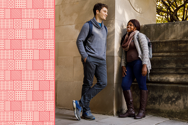 Two students of different genders and races stand by a campus building chatting.