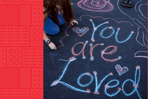 A chalk drawing includes hearts and flowers and reads you are loved.