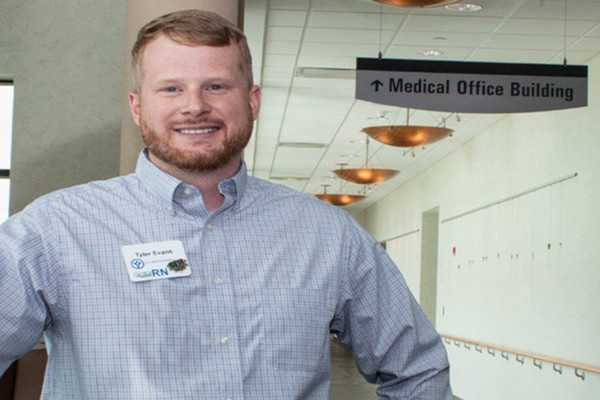 Tyler Evans wearing his nurse administrator badge in a hospital corridor.