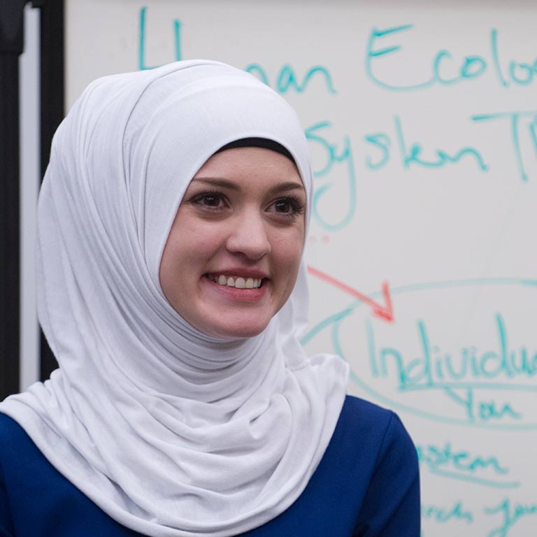 A smiling woman wearing a headscarf